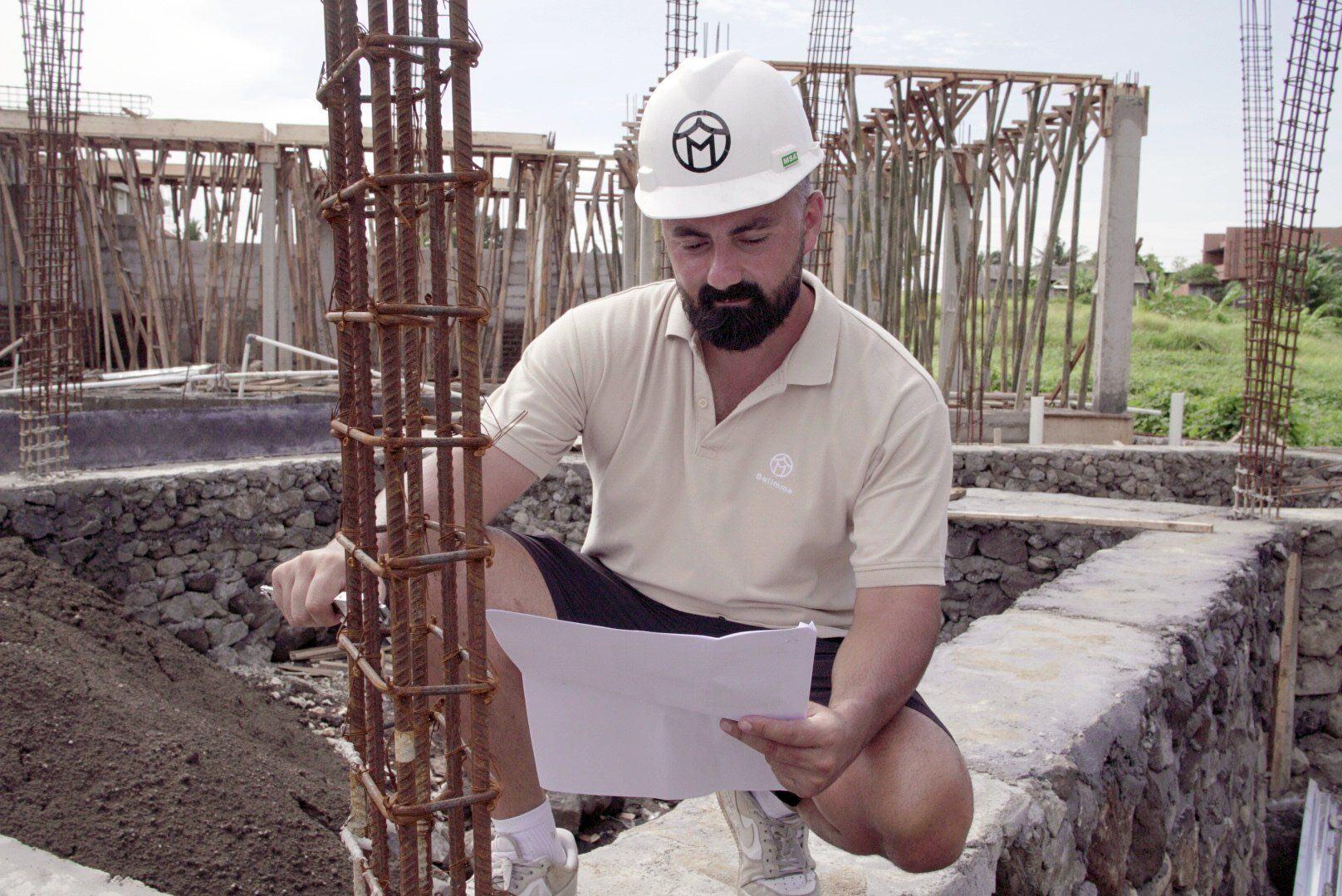 Chef de chantier Balimmo consultant les plans sur un chantier de villa à Bali